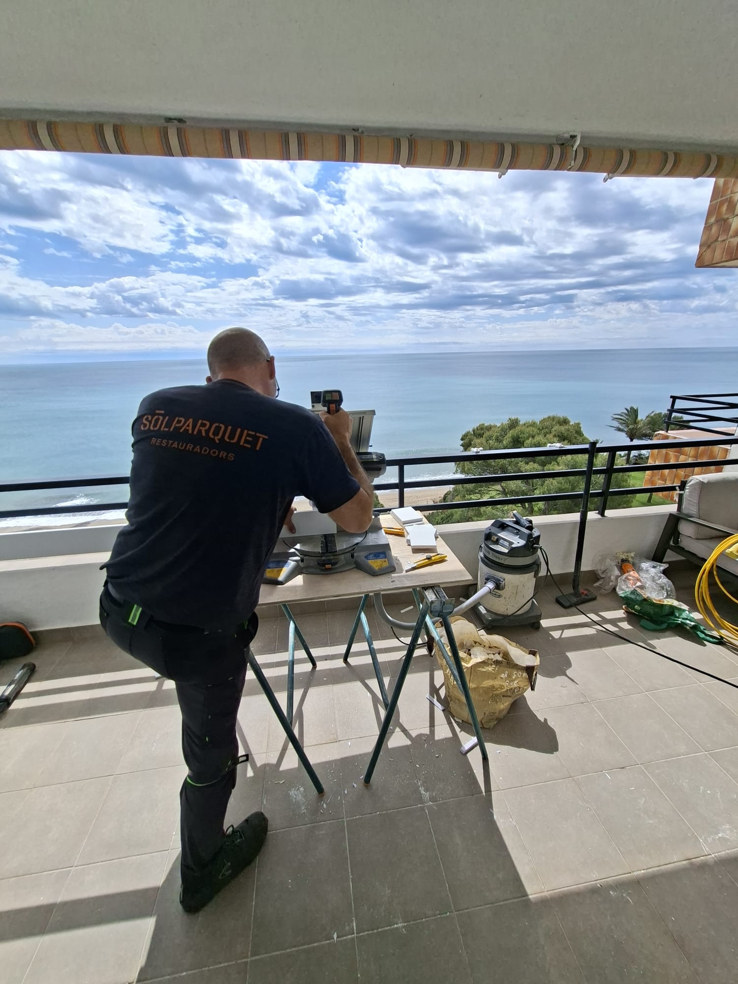 Operari de Solparquet treballant en una terrassa amb vistes al mar